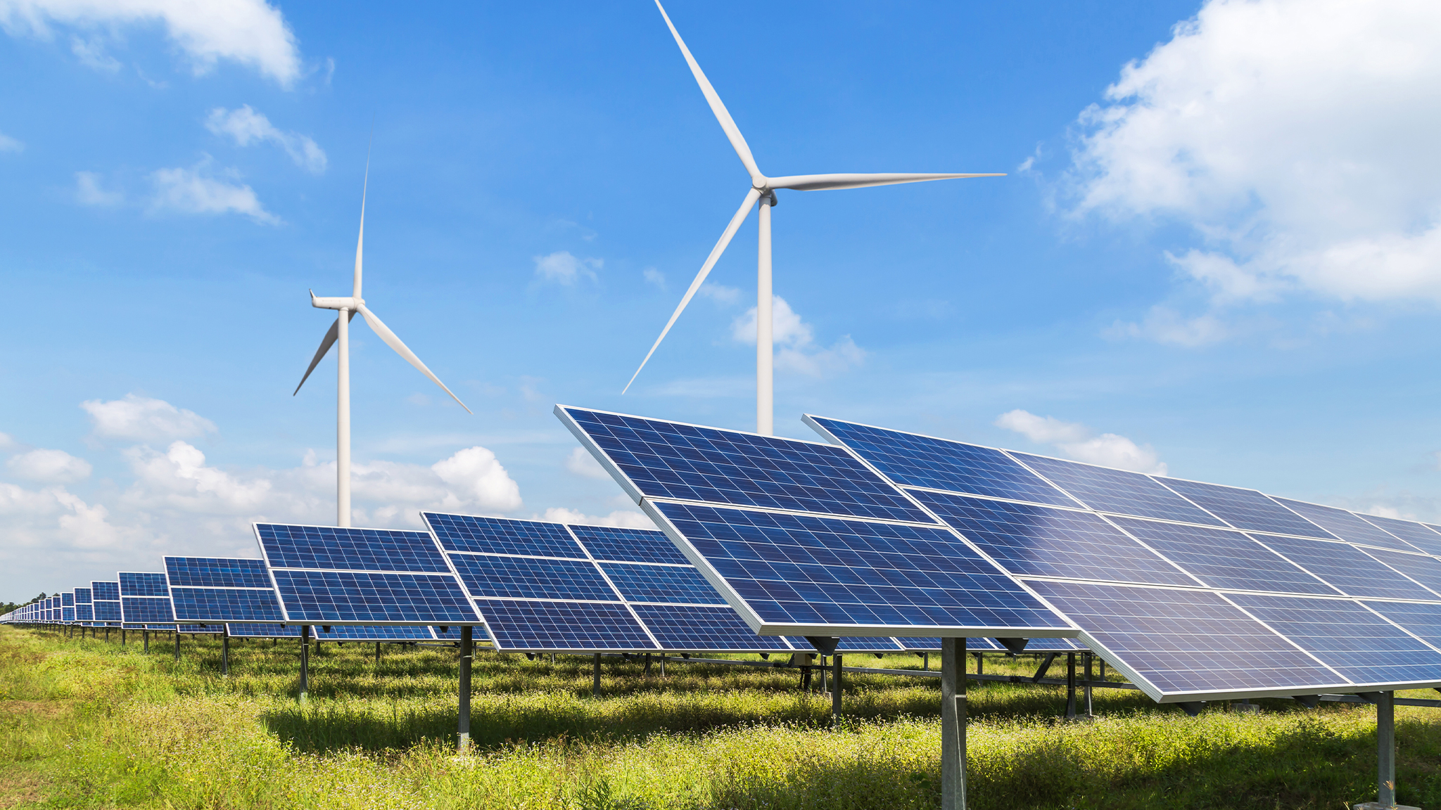 solar panels and wind turbines generating electricity in power station green energy field with blue sky background